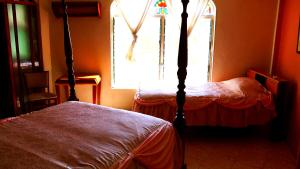 a bedroom with a four poster bed and a window at Banana Bank Lodge & Jungle Horseback Adventures in Belmopan
