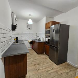 a kitchen with a stainless steel refrigerator and wooden cabinets at Apartament Tuwima 1 in Prudnik