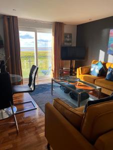 a living room with a couch and a table at CockleDora, A Luxury Ground Floor Beachfront Apartment in Llanelli