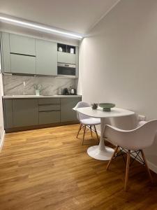 cocina con mesa blanca y sillas en una habitación en The Captain's Apartments SIROCCO - CITY CENTER Leonardo Academy, en Sesto Calende