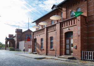 a brick building with umbrellas on the side of it at Stay in a Historical Train Station up to 10 beds in Halbe