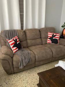 un sofá marrón con 2 almohadas en la sala de estar en Marie Guest House (A/C entire house), en Camuy