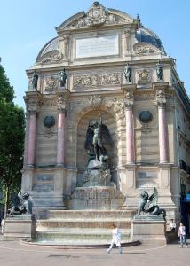 a person walking in front of a building with a fountain at Paris Centre Place Saint Michel in Paris