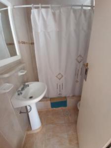 łazienka z białą zasłoną prysznicową i umywalką w obiekcie Trujui Host w mieście Termas de Río Hondo