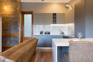 eine Küche mit blauen Schränken und einem Tisch und einem Sofa in der Unterkunft Canto do Atlântico Loft (City Centre) in Ponta Delgada