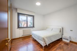 a white bedroom with a bed and a window at Beccaria17 in Parma