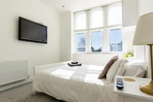 a white bedroom with a bed and a flat screen tv at ST MARYS APARTMENT - Modern Apartment in Charming Market Town in the Peak District in Penistone