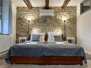 a bedroom with a bed with two lamps and a stone wall at Vitamin K73 Vendégház in Boldogkőváralja