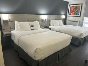 Habitación de hotel con 2 camas y almohadas blancas en Quality Inn en Leamington