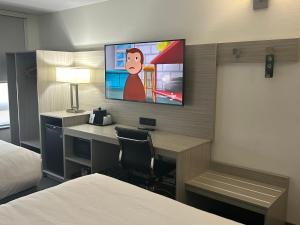 a hotel room with a desk and a tv on the wall at Quality Inn Leamington in Leamington