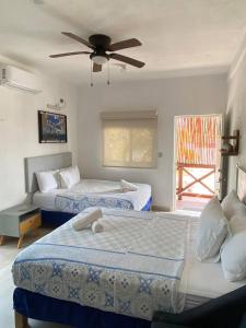 Casa Coronaa Holbox México في جزيرة هول بوكس: غرفة نوم بسريرين ومروحة سقف