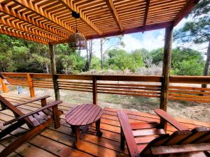 a porch with chairs and tables and a view of the forest at Lobos de Mar in Punta Del Diablo