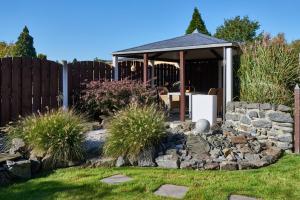 a garden with a gazebo and a stone wall at Ferienwohnung Haaren in Waldfeucht