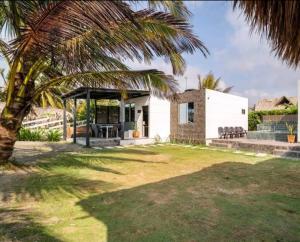 a white house with a palm tree in a yard at AGUAMARINA House in San Bernardo del Viento