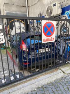een blauwe auto geparkeerd naast een hek met een bord bij Apartment in Belgrade with small parking space in Belgrado