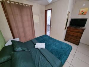 um quarto com uma cama verde e uma televisão em Pousada Zênit Peró II em Cabo Frio