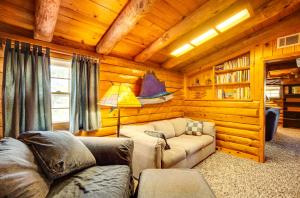 Sala de estar con sofá y lámpara en una cabaña en Waterfront Livingston Log Cabin with Private Dock!, en Blanchard
