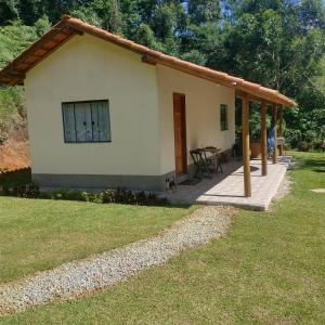 a small house with a porch and a table at Chalé encontro dos rios in Nova Friburgo