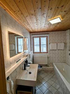 a bathroom with a tub and a sink and a bath tub at Ferienwohnung Alpenblick Dorner in Oberreute