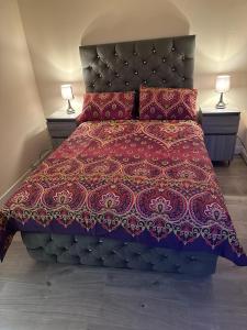 een bed met een rood dekbed en 2 lampen bij ELSARO guest house in Slough