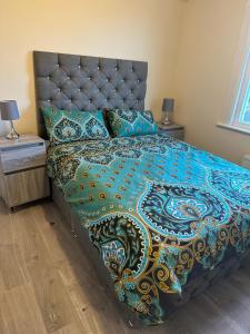 a bedroom with a bed with a colorful comforter and pillows at ELSARO guest house in Slough