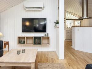 Holiday home Ansager X في Ansager: غرفة معيشة مع طاولة وتلفزيون على الحائط