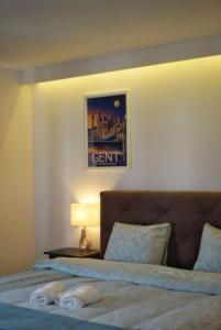 een slaapkamer met een bed met een lamp en een foto bij Arku apartments Brussels Airport in Zaventem