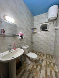 a bathroom with a white toilet and a sink at Bait Al-Bustan Umm Qais in Um Qeis