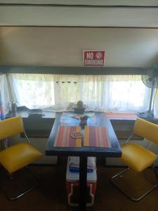 a table with two yellow chairs and a no smoking sign at Backpack Cabin A 49149 in Oranjestad