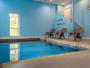 una piscina con sillas y una pared azul en Elegant Elite Estate By Ghosal Luxury Lodging, en Pigeon Forge