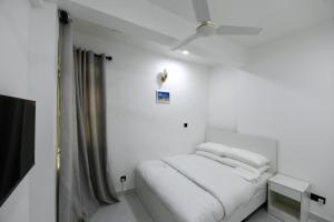 a white bedroom with a bed and a ceiling fan at Seaview Apartment by Lin Residences in Male City