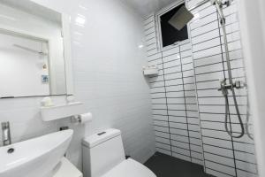 a white bathroom with a toilet and a sink at Seaview Apartment by Lin Residences in Male City