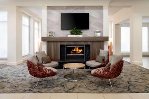 a living room with a fireplace and a tv at Hilton Garden Inn Roseville in Roseville