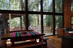 a living room with a table and a person sitting on the porch at El Refugio de Hadas y Elfos in Puerto Fuy