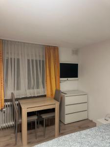 een kamer met een tafel, een bureau en een televisie bij Zimmer mit eigener Dusche & WC , beim Stausee in Schömberg