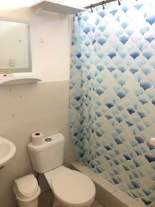 y baño con aseo y cortina de ducha. en Pargo, habitación privada de Flor de Lis Beach House, en Playas