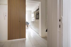 a hallway with a kitchen with white walls and a wooden door at Zentrales Apartment am Nordertor in Flensburg