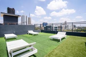 a rooftop patio with white benches and grass at Laurel Hill Suites in Nairobi
