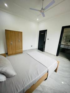 ein großes Bett in einem Zimmer mit Deckenventilator in der Unterkunft DSD-Apartments in Brusubi