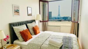 une chambre avec un lit avec des oreillers orange et une fenêtre dans l'établissement paris holiday, à Aubervilliers