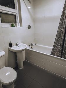 a bathroom with a toilet and a sink and a bath tub at Spacious 3 rooms in Tooting in London