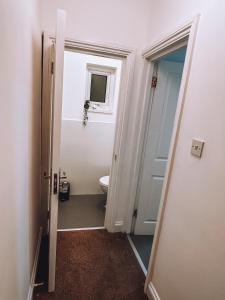 a bathroom with a toilet and a window and a door at Spacious 3 rooms in Tooting in London