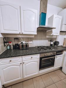 a kitchen with white cabinets and a stove top oven at Spacious 3 rooms in Tooting in London