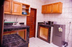 - une cuisine équipée d'une cuisinière, d'un évier et de placards dans l'établissement J&G Premier Apartment, à Yaoundé