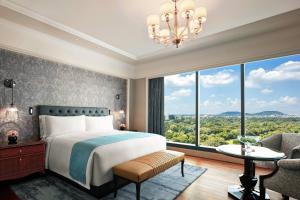 プネにあるThe Ritz-Carlton, Puneのベッドルーム1室(ベッド1台、大きな窓付)