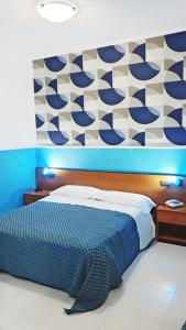 una camera con un letto con una parete blu e bianca di Hotel Blu Eden a Praia a Mare