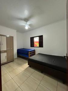 een slaapkamer met een blauw bed en een raam bij Sinuca, churrasqueira e fogueira a 300 metros do mar in Itanhaém