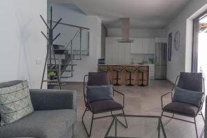 a living room with a couch and chairs and a kitchen at VILLA caracolillo MAR in Chiclana de la Frontera