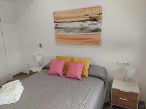a bedroom with a bed with pink and yellow pillows at VILLA caracolillo MAR in Chiclana de la Frontera +48 photos