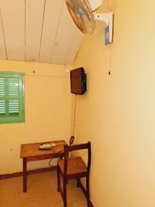 Habitación con mesa, TV y silla. en Auberge Mariama BA en Gorée